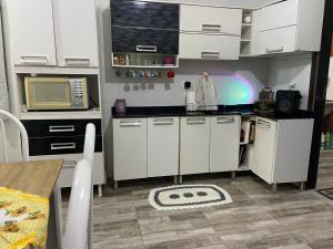 a kitchen with white cabinets and a microwave at Mara e Jorge Suites Beira Mar in Cananéia +12 photos