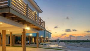 een gebouw op het strand met een zonsondergang op de achtergrond bij 2 Homes Sleeps 22 2 Private Pools Firepit Steps to Beach Boardwalk Access in Mustang Beach