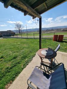 a table and a chair on a porch with a view of a field at D&D Apartment in Koceljevo
