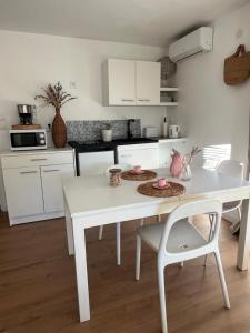 eine weiße Küche mit einem weißen Tisch und Stühlen in der Unterkunft Studio au dernier étage d'une bastide grassoise in Grasse + 2 Fotos