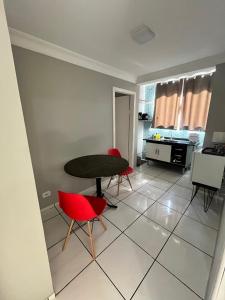 a living room with a table and red chairs at kitnet Nostradamus in Barão de Cocais