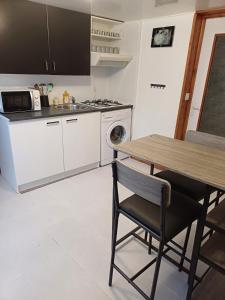 eine Küche mit einem Tisch, einem Herd und einer Mikrowelle in der Unterkunft Agréable studio au rez de chaussée in Arbois