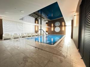 een zwembad in een hotelkamer met witte stoelen bij Dune & Sea in Ustronie Morskie