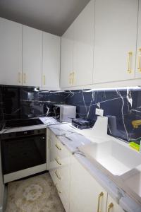 a kitchen with white cabinets and black appliances at Golden Apartment Korce in Korçë