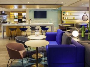 a lobby with a blue couch and tables and a bar at Mercure Rouen Centre Cathédrale in Rouen