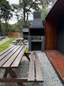 a picnic table with a grill next to a building at La Posada Bungalows in Necochea