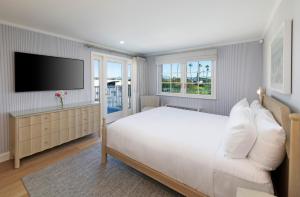a bedroom with a large white bed and a flat screen tv at Bay Shores Peninsula Hotel in Newport Beach +87 photos