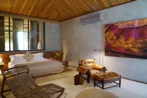 a bedroom with a bed and a couch and a chair at Primitivo Hotel & Villas in Passo de Camarajibe