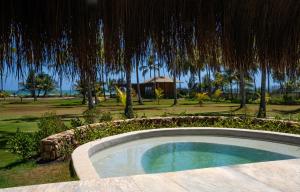 a small swimming pool in a resort with an umbrella at Primitivo Hotel & Villas in Passo de Camarajibe
