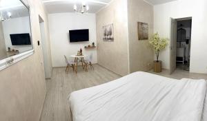 a white bedroom with a bed and a table at Cleo Residence 2 Ghiroda in Ghiroda