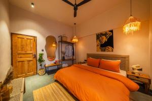 a bedroom with an orange bed and a wooden door at ONEOFF X ASSI - A Boutique Homeotel in Varanasi