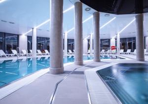 une piscine dans un immeuble avec des chaises blanches dans l'établissement Apartment Snow & Spa Czarna Góra Resort, à Sienna
