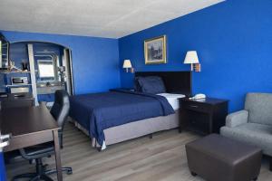 een blauwe slaapkamer met een bed, een bureau en een stoel bij Apollo Lodge and RV Park in Fairfield
