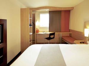 a bedroom with a bed and a desk and a chair at Hotel ibis Lisboa Jose Malhoa in Lisbon