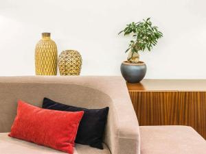 un divano con due vasi e una pianta in vaso di Hotel Ibis Coimbra Centro a Coimbra