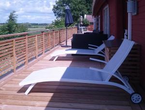 een terras met 2 ligstoelen en een parasol bij Unikt sommarboende in Färjestaden