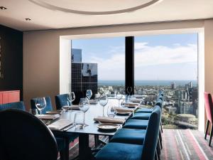 une salle à manger avec une grande table, des chaises et une grande fenêtre dans l'établissement Sofitel Melbourne On Collins, à Melbourne