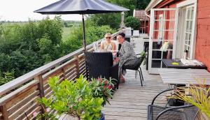 twee mensen zitten aan een tafel onder een parasol op een terras bij Unikt sommarboende in Färjestaden +19 foto's