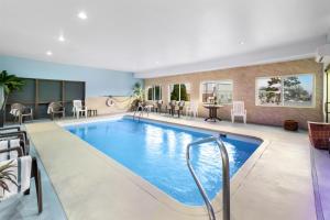 een zwembad in een hotelkamer met stoelen en een tafel bij Red Lion Inn & Suites Blue Springs in Blue Springs
