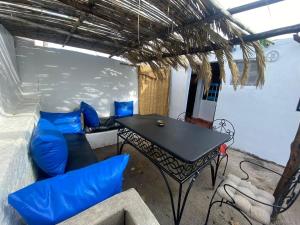 a room with a table and a couch and blue chairs at Studio Surf House Kaouki in Sidi Kaouki