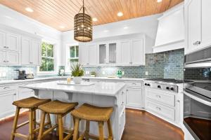 a kitchen with white cabinets and a large island with stools at Seagrove Sun in Santa Rosa Beach