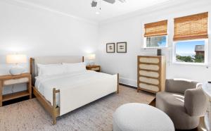 a white bedroom with a bed and a chair at Seagrove Sun in Santa Rosa Beach