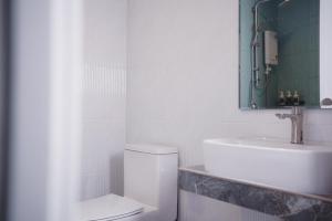 een witte badkamer met een wastafel en een toilet bij Sinapa Suites in Ko Pha Ngan