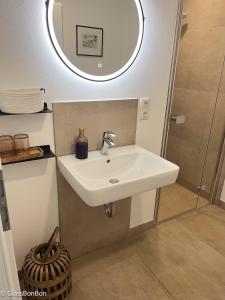 un lavandino bianco in un bagno con uno specchio di Altstadtflair Modernes Studio mit Gartenblick a Neuruppin