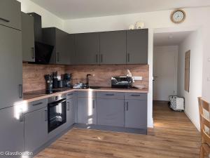 a kitchen with stainless steel appliances and wooden floors at Altstadtflair Modernes Studio mit Gartenblick in Neuruppin