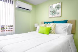 een slaapkamer met een groot wit bed met groene accenten bij The Dorset on Ashby in Chaguanas Village