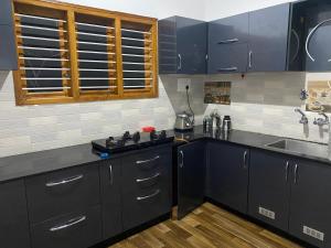 eine Küche mit dunkelblauen Schränken und einem Waschbecken in der Unterkunft Jk homestay Mysore in Mysore