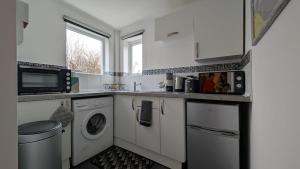 une cuisine blanche avec un lave-linge et un sèche-linge. dans l'établissement Seaford Snug, à Seaford