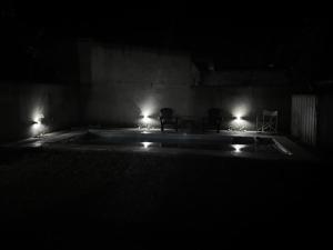 a dark room with a pool with two chairs and lights at Casa quinta in Dolores