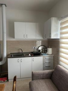 a kitchen with white cabinets and a sink and a couch at Verina kuća in Kosjerić