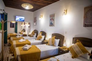 a room with four beds with yellow and white sheets at Shauala Riad - Where History Lives in Fès