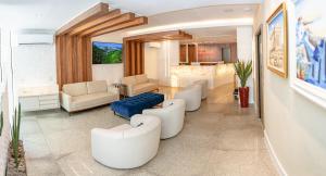 een woonkamer met witte stoelen en een blauwe bank bij Hotel Santorini in Vila Velha