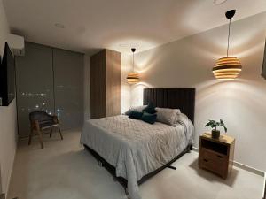 een slaapkamer met een bed en 2 hanglampen bij doca brisa in Santa Marta