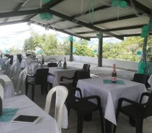 a banquet hall with white tables and chairs and bottles of wine at Ecohotel Los Cedros in Cocorná
