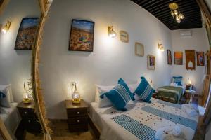 a bedroom with a bed with blue pillows and a mirror at Shauala Riad - Where History Lives in Fès