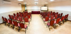 una sala conferenze con sedie rosse e schermo di Hotel Santorini a Vila Velha Altre 73 foto