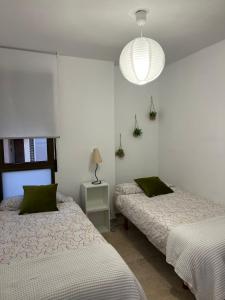 a bedroom with two beds and a light fixture at La Llum de Serra in Serra