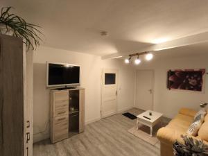 een woonkamer met een bank en een flatscreen-tv bij FeWo Antweiler Unterdorf in Mechernich