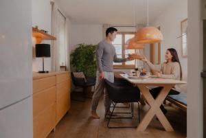 a man and woman standing in a kitchen with a table at Villa Tegernsee - Exclusive Lakefront Villa with private Zirben Sauna, 4 Rooms for Family & Friends in Tegernsee