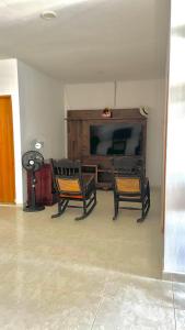 a living room with two chairs and a flat screen tv at Alojamientos Fredys in Santa Cruz de Mompox