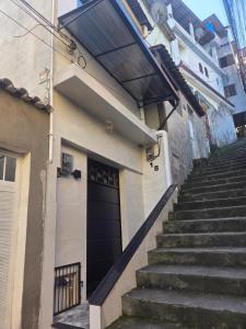 a stairway leading to a black door on a building at Sua Estadia Angra - Casa de 2 Quartos no Centro de Angra in Angra dos Reis