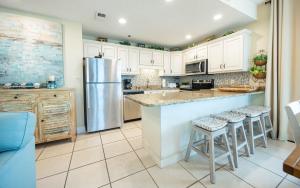 a kitchen with a stainless steel refrigerator and stools at Phoenix East 1211 in Orange Beach +45 photos