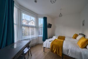 a bedroom with a bed and a desk and windows at Chapel Road Cosy Rooms & Studios in Hounslow