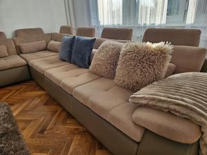 a brown couch with pillows on it in a living room at FAMILLE Apartman in Tapolca