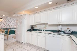 a kitchen with white cabinets and a refrigerator at Phoenix East 1401 in Orange Beach