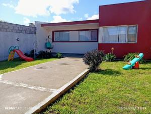 a red house with a playground in the yard at Departamentos Necochea in Necochea